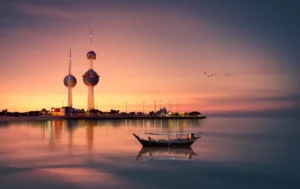 Couché du soleil au Kowait avec la skyline en fond au bord de mer avec un petit bateau au mieux
