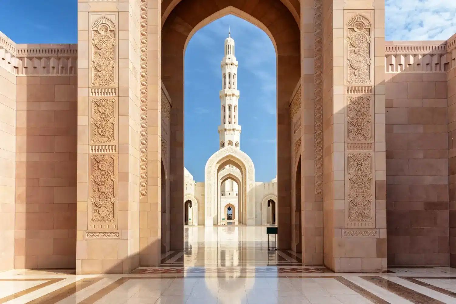 Vue d'un minaret à travers les arches de la Grande Mosquée Sultan Qaboos.