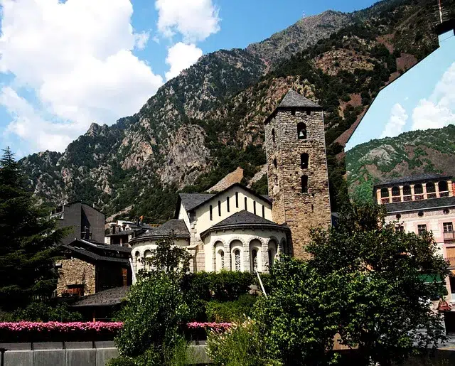 Église typique en pierre au cœur d’Andorre-la-Vieille, entourée de montagnes, représentant le patrimoine culturel du pays où flotte souvent le drapeau andorran