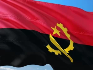 Le drapeau de l’Angola flottant au vent, composé d’une bande rouge et noire avec un emblème jaune représentant une machette, une roue dentée et une étoile.
