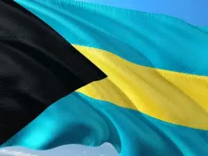 Drapeau des Bahamas bleu, noir et jaune flottant dans le ciel, symbole national et identitaire de l’archipel.