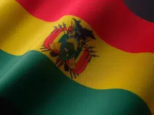 Gros plan sur le drapeau de la Bolivie aux couleurs rouge, jaune et vert avec les armoiries nationales, symbole fort de l’identité bolivienne.