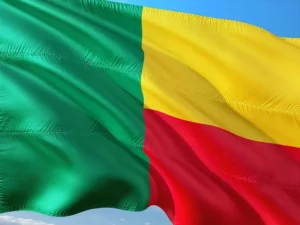 Le drapeau du Bénin flottant au vent, affichant ses trois couleurs symboliques : vert à gauche, jaune en haut à droite et rouge en bas à droite, représentant l’identité nationale béninoise