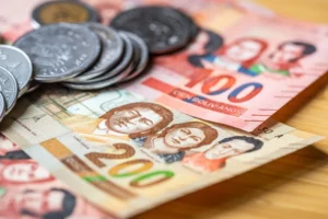 Pièces et billets de monnaie en Bolivie, avec des coupures de 100 et 200 bolivianos mettant en avant des figures historiques boliviennes.