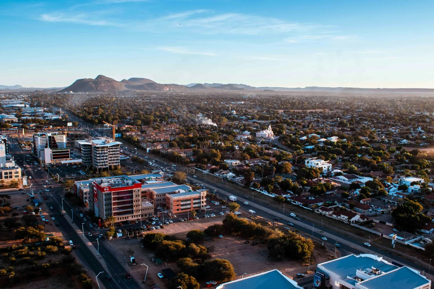 Vue aérienne de la ville de Gaborone au Botswana avec ses bâtiments modernes, routes et quartiers résidentiels sous un ciel dégagé.