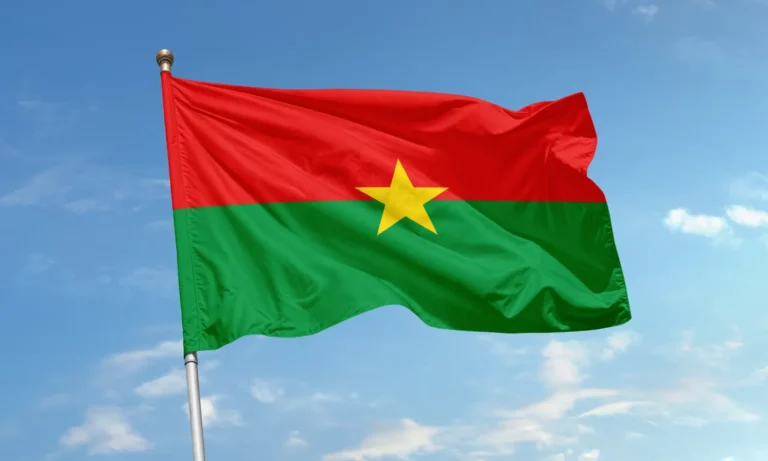 Drapeau du Burkina Faso, composé de deux bandes rouge et verte avec une étoile jaune au centre, flottant sur fond de ciel bleu.