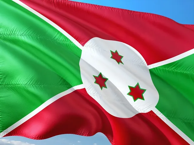 Drapeau national du Burundi flottant au vent, composé de vert, rouge et blanc avec trois étoiles rouges à contour vert au centre.