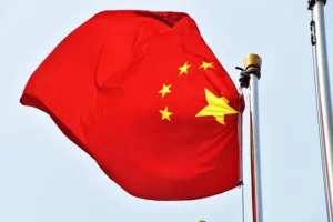 Drapeau chinois rouge avec étoiles jaunes flottant au vent sous un ciel bleu