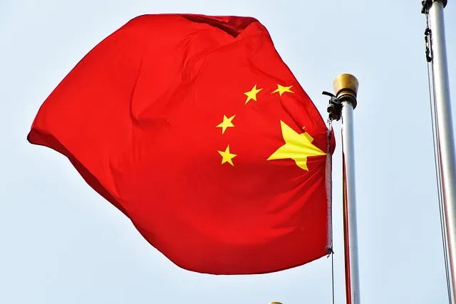 Drapeau chinois rouge avec étoiles jaunes flottant au vent sous un ciel bleu