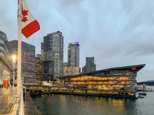 Ville Canada Vancouver – Vue du port de Vancouver avec ses gratte-ciel modernes illuminés et un drapeau du Canada au premier plan