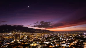 Vue nocturne de San José, capitale du Costa Rica, illuminée sous un ciel coloré.