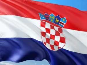 Drapeau de la Croatie flottant au vent avec ses bandes rouge, blanche et bleue et les armoiries nationales au centre.